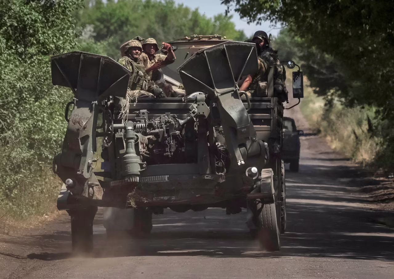 Ukrainian servicemen ride on a military vehicle as they tow an M777 155 mm howitzer near the front line in the Donbas region, Ukraine, on July 12.