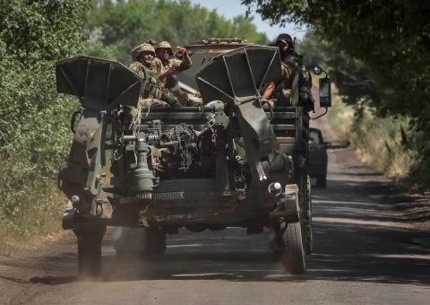 Ukrainian servicemen ride on a military vehicle as they tow an M777 155 mm howitzer near the front line in the Donbas region, Ukraine, on July 12.