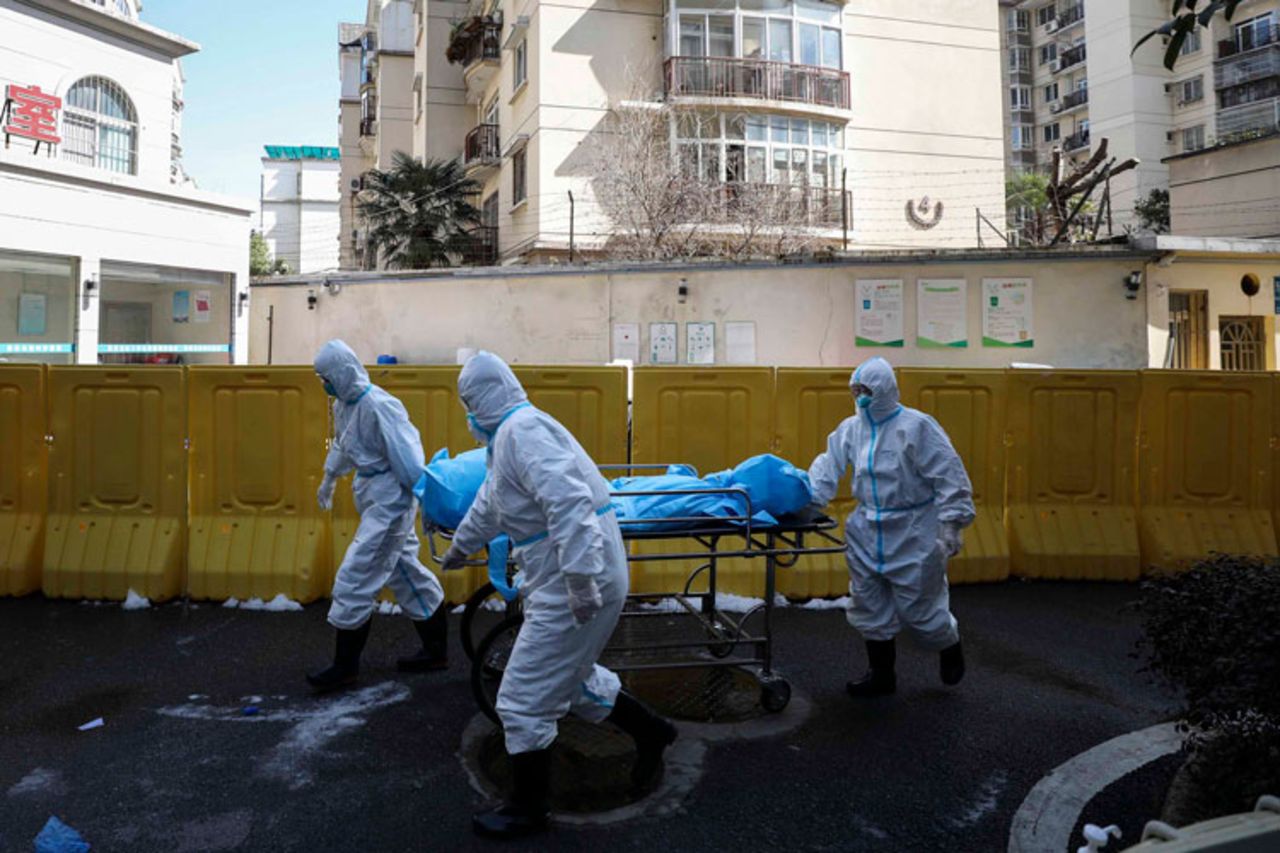 Medical workers move a person who died from COVID-19 at a hospital in Wuhan in central China's Hubei province on Sunday, February 16.