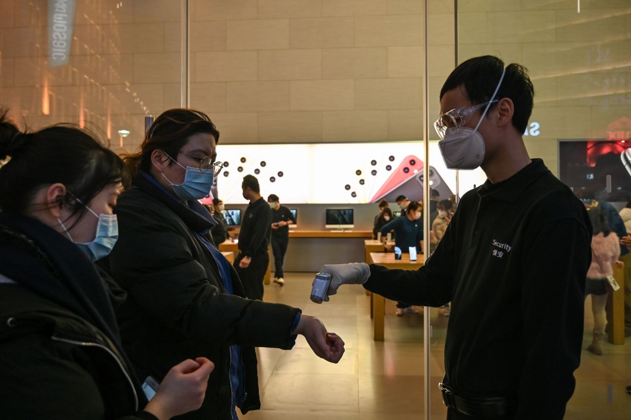 A security guard checks the temperature of customers at the entrance of an Apple store in Shanghai on February 25.