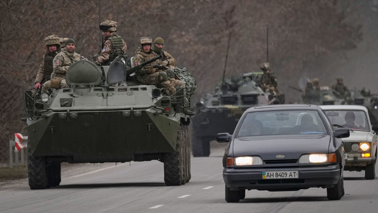 Ukrainian service members sit atop armored personnel carriers Thursday as they drive on a road in the Donetsk region.