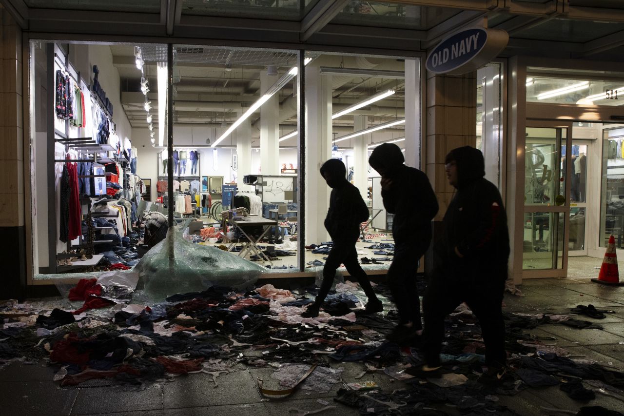 People walk past a looted store in Seattle on May 30.