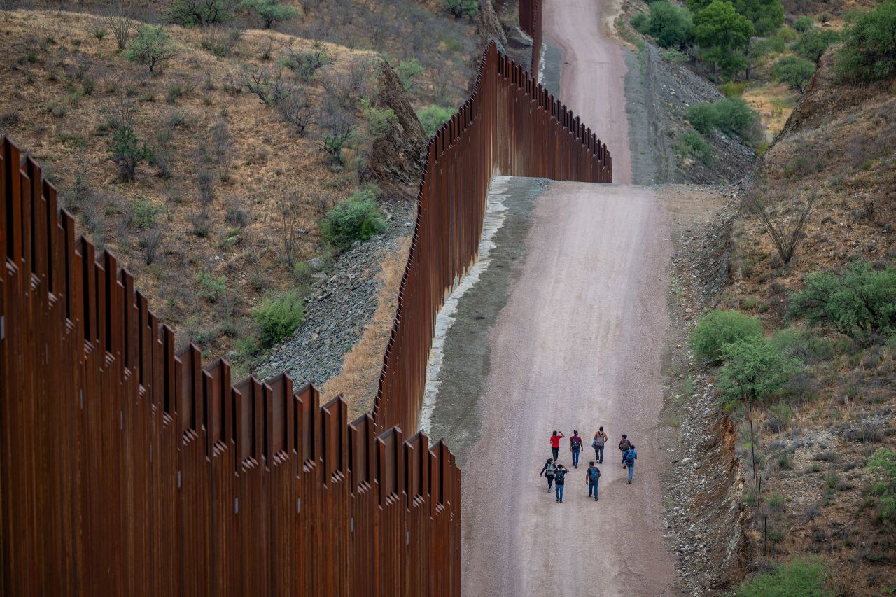 Migrants seeking asylum from Central and South America walk alongside border fencing after illegally crossing over into the U.S. on June 24, in Ruby, Arizona. 