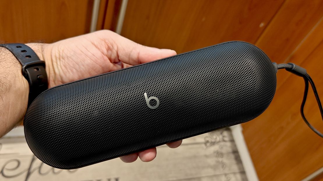 A black Beats Pill speaker in someone's left hand.