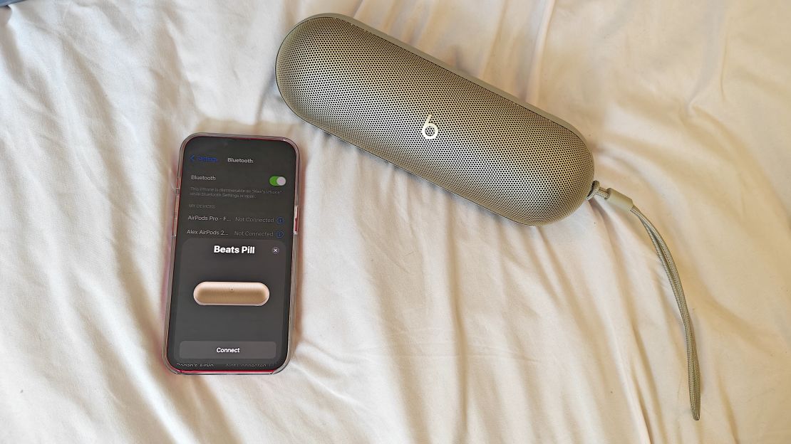 A Beats Pill and an iPhone on a bed.