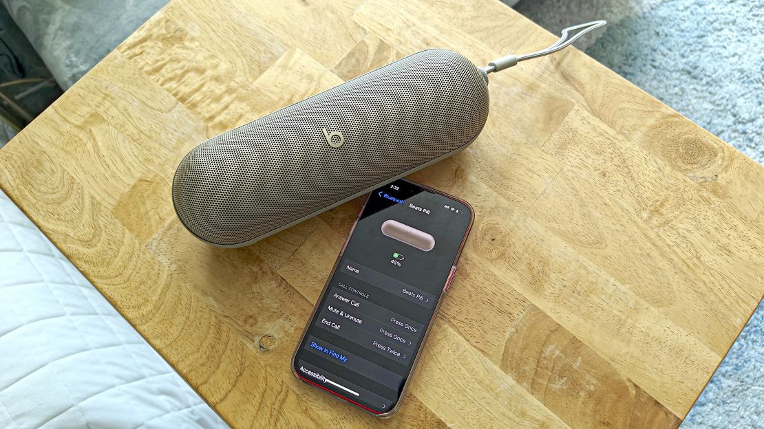 A Beats Pill speaker and an iPhone on a wooden surface.