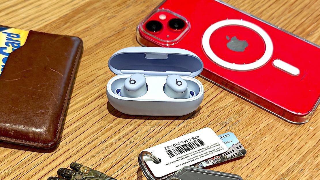 The Beats Solo Buds in case with lid open, next to a wallet, phone and keys