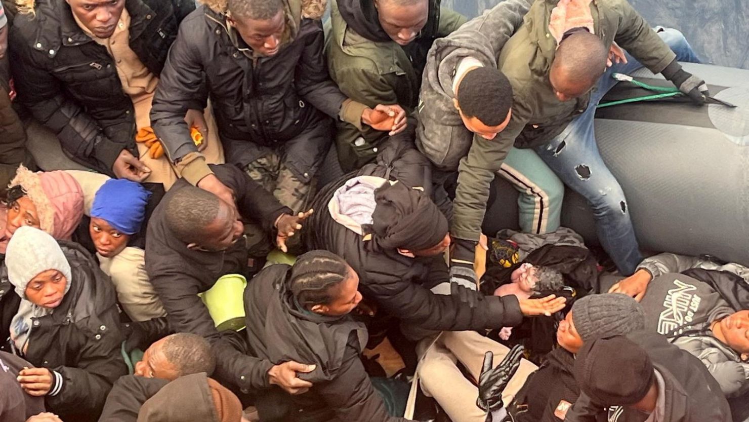 Un migrante sostiene a una bebé recién nacida mientras una mujer yace dentro de un bote de goma con otros migrantes que fueron rescatados frente a la isla canaria de Lanzarote en España, el 6 de enero de 2025.