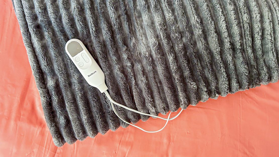 The Bedsure Electric Heated Thick Striped Blanket and its remote flat on a bed.