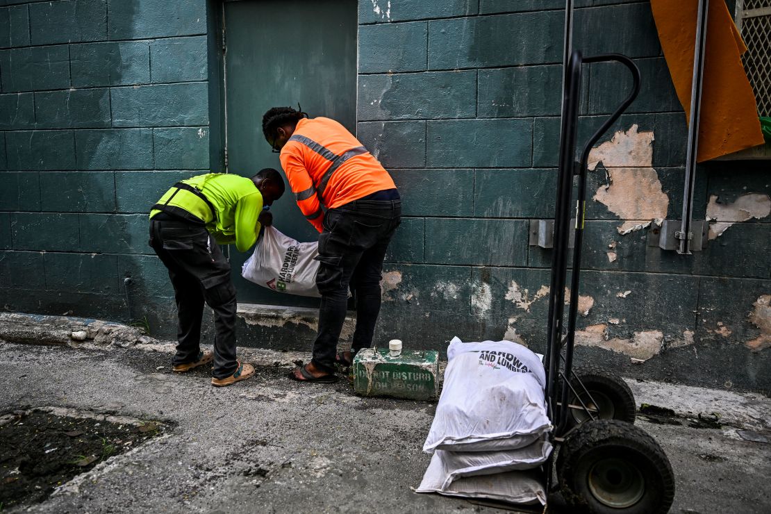 Workers put bags of sand at the back door of a shop on Sunday in preparation for the arrival of Hurricane Beryl in Bridgetown, Barbados.