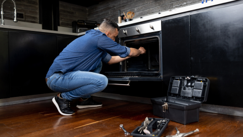Electrician repairing an oven in a home kitchen