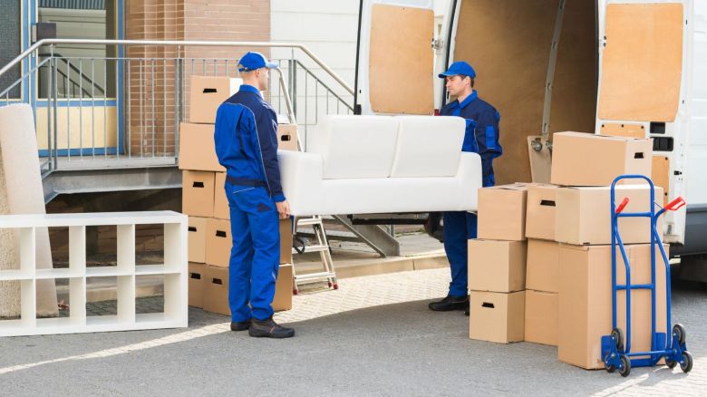 Two movers unloading a couch from a moving van