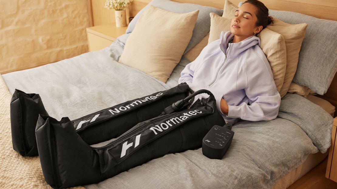 Woman on bed wearing compression boots.