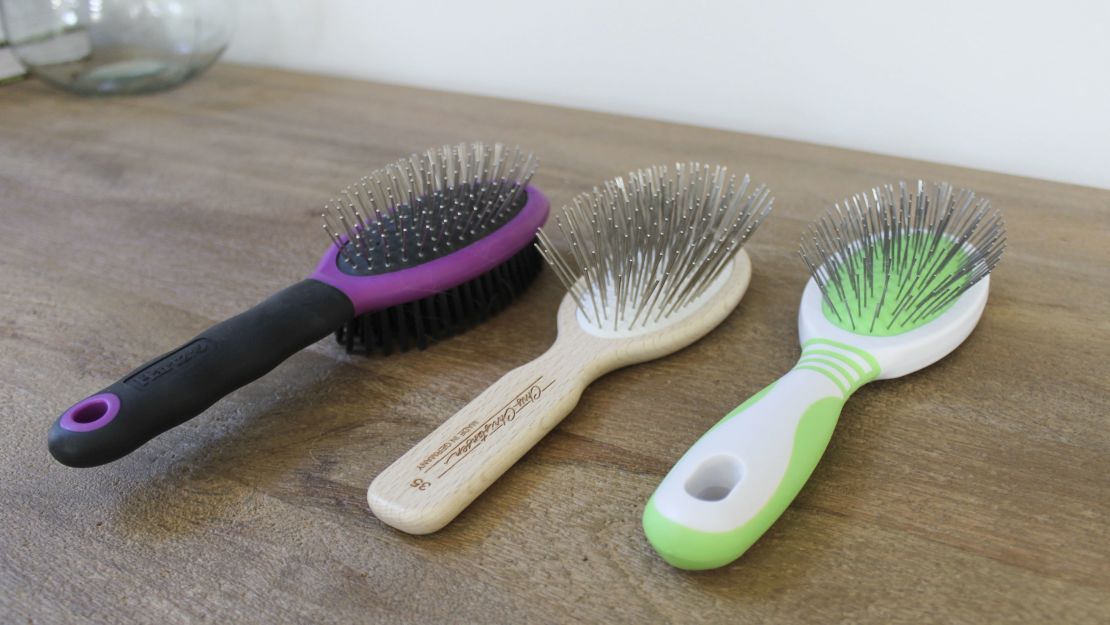 Three pin brushes on a wooden surface.