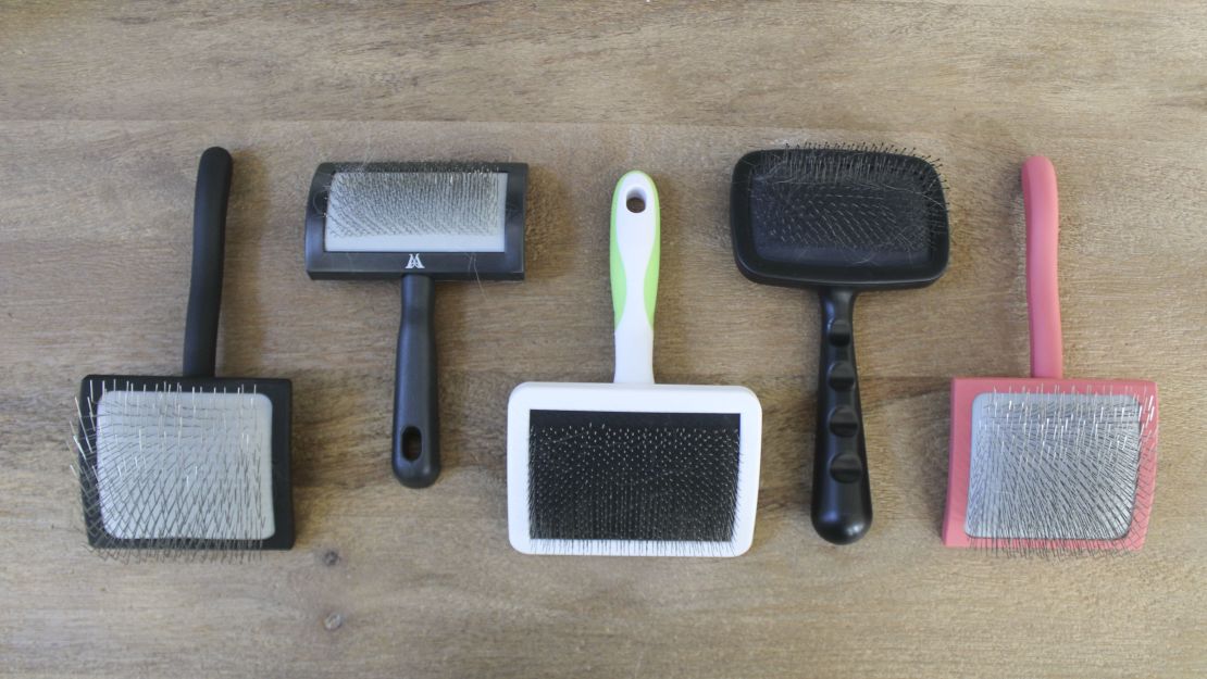 Five slicker brushes on a wooden surface.