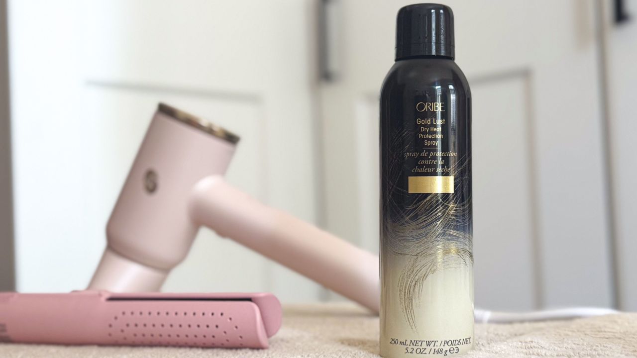 Bottle of Oribe Gold Lust Dry Heat Protection Spray with hair styling tools