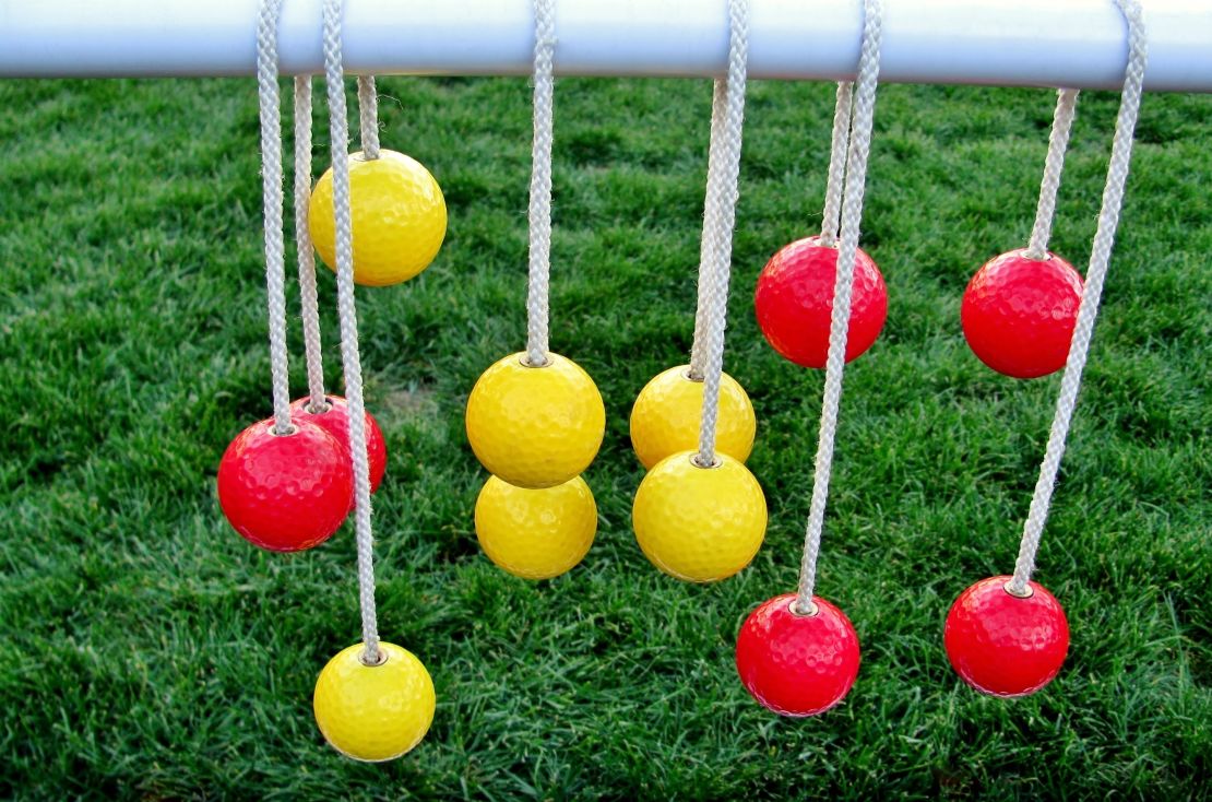 Yellow and red balls hanging on the ropes against green grass