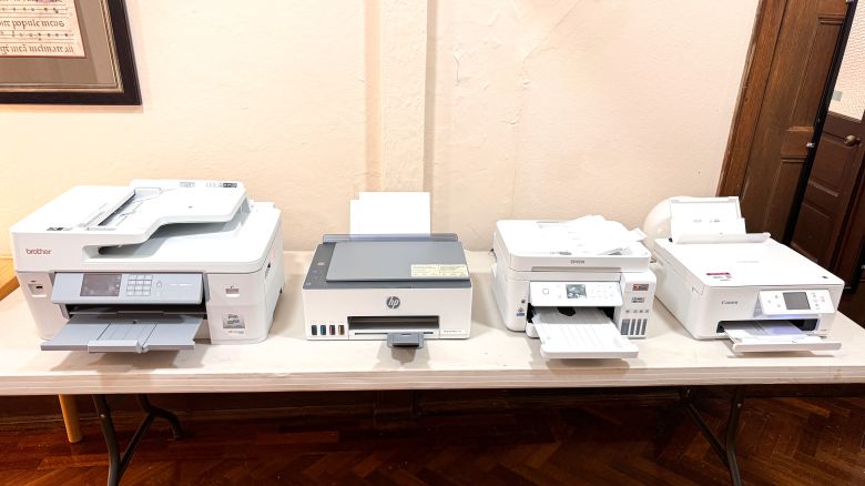 Four white printers displayed on a table