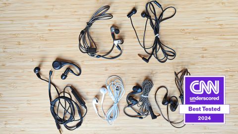 Seven pairs of wired earbuds on a wooden surface.
