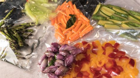 Vacuum-sealed bags of asparagus, carrots, zucchini, peppers and shallots, for sous vide cooking.