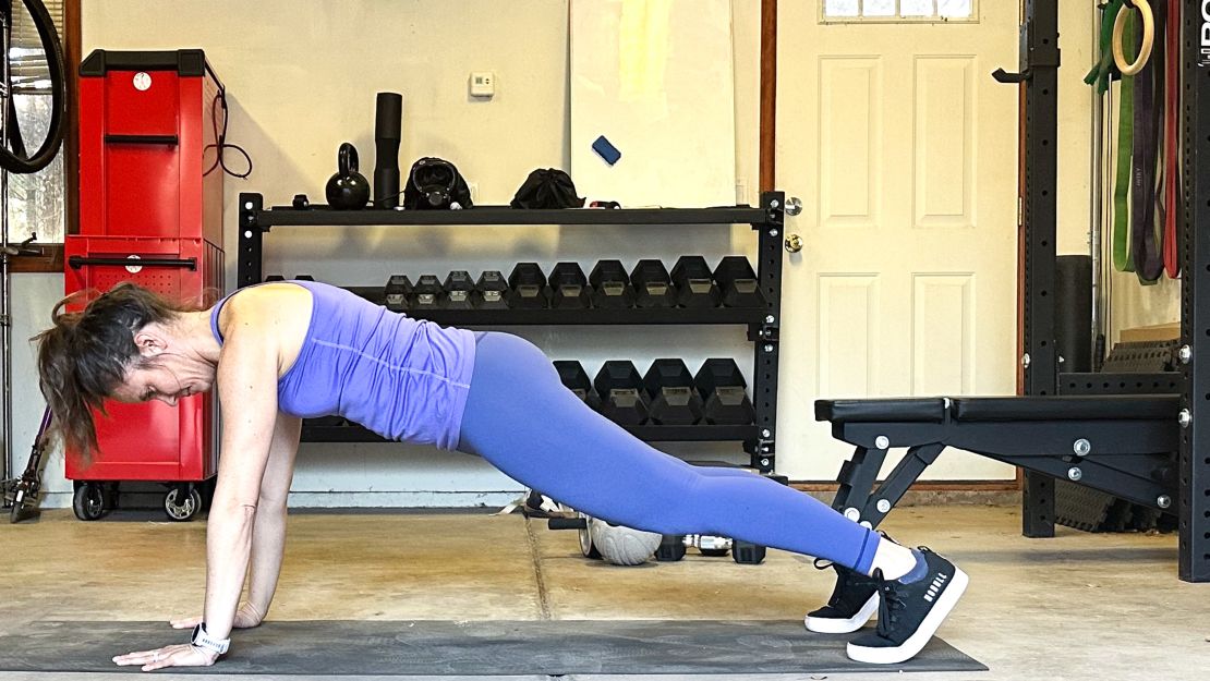 A woman exercising on a mat in a garage.