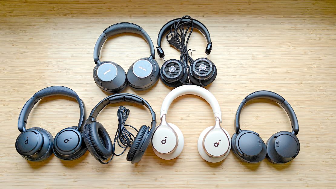 Six pairs of headphones on a wooden desk.