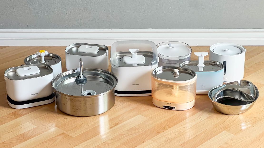 Ten water fountains for cats and dogs on wooden floor.