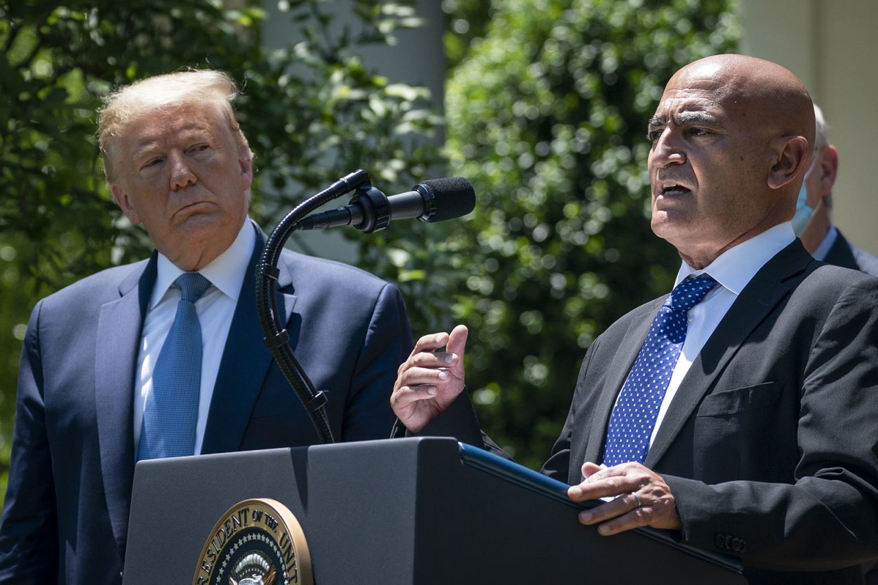 President Donald Trump listens as Moncef Slaoui, the former head of GlaxoSmithKlines vaccines division, speaks about coronavirus vaccine development in the Rose Garden of the White House on May 15, in Washington.