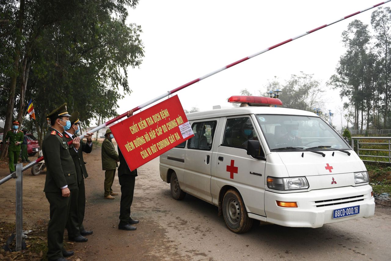 Police wearing face masks allow an ambulance to pass through a checkpoint at the Son Loi commune in Vinh Phuc province on February 13, 2020.