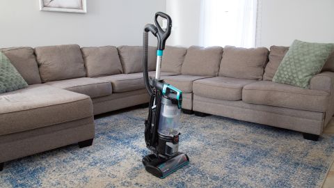 Bissell Pet Hair Eraser Lift-Off Upright Pet Vacuum in front of a sectional couch