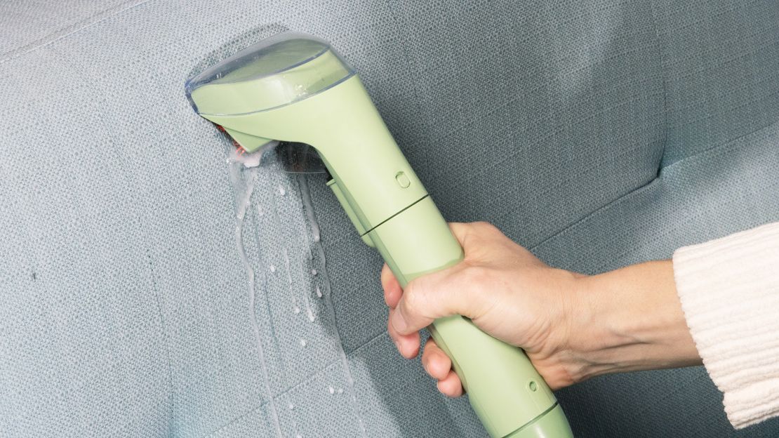 The Bissell Little Green Portable Carpet Cleaner uses water to clean a couch.