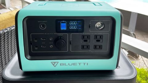 A bluish-green Bluetti EB70S solar generator set up on a patio, showing an 80% charge.