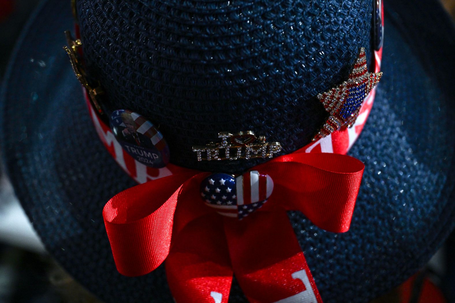 A woman wears a hat with Trump's name on it.