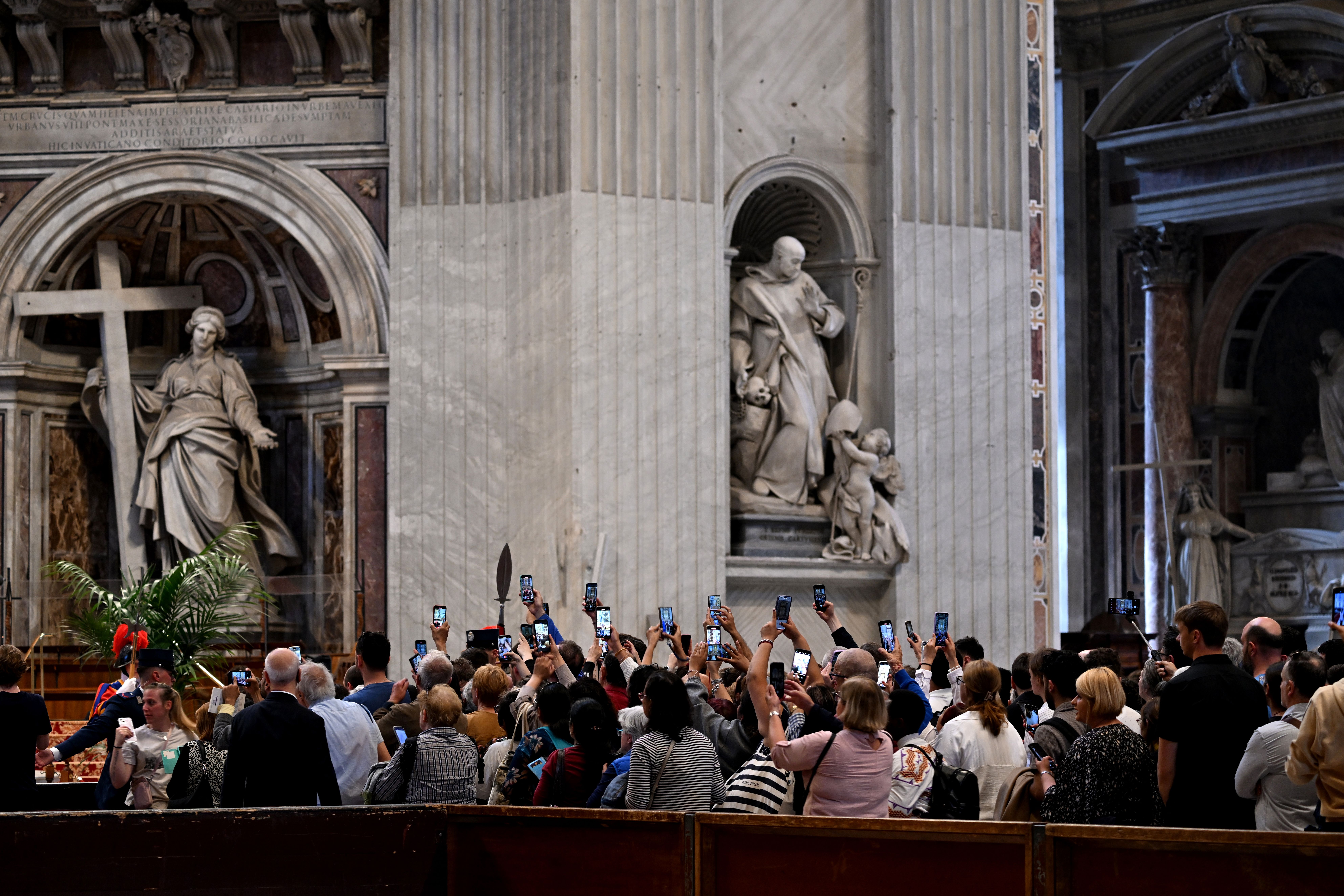 People hold up their mobile devices as they view the the pope's body in St. Peter's Basilica.