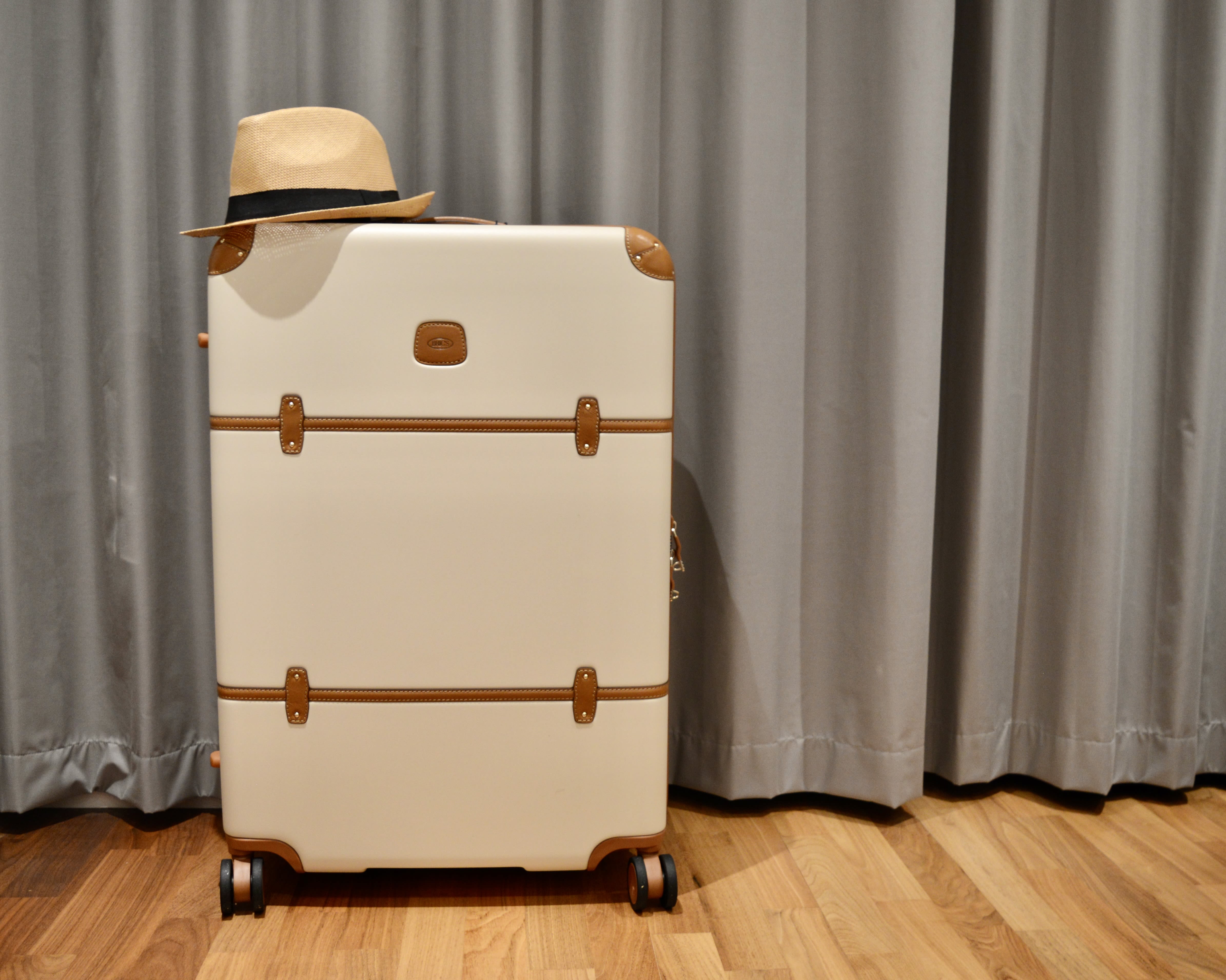 A photo of a Bric's suitcase with a hat on top