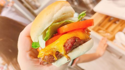 A close up of a charcoal-grilled burger, demonstrating the cooking ability of a Weber charcoal grill.