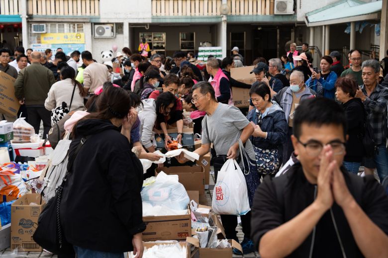 A man prays as residents collect donations at a distribution point following the fire at Wang Fuk Court housing complex in Tai Po, Hong Kong, on November 27, 2025.