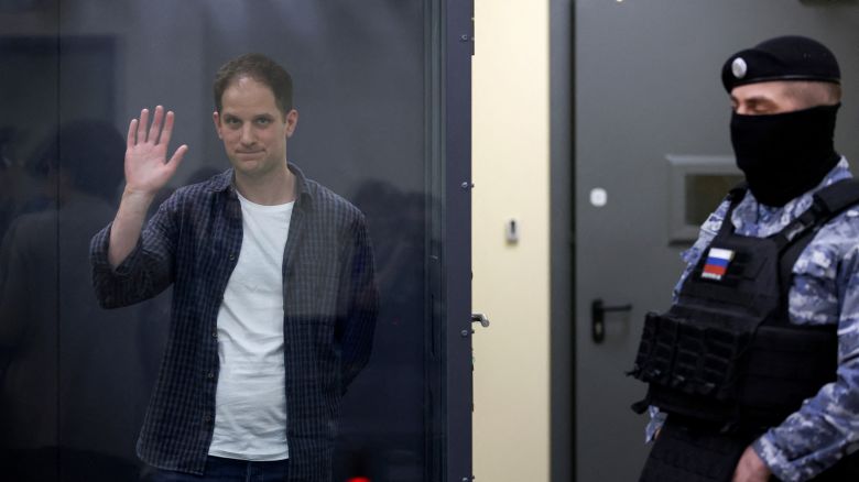 Wall Street Journal reporter Evan Gershkovich waves behind a glass wall of an enclosure for defendants as he attends a court hearing in Moscow, Russia, on April 23.