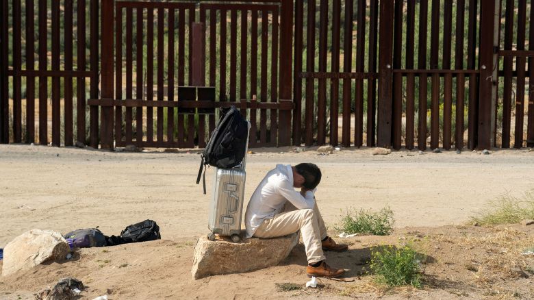 An asylum-seeking migrant from China rests on a rock while waiting to be transported by the US Border Patrol after crossing the border from Mexico into the in Jacumba Hot Springs, California, on June 4.