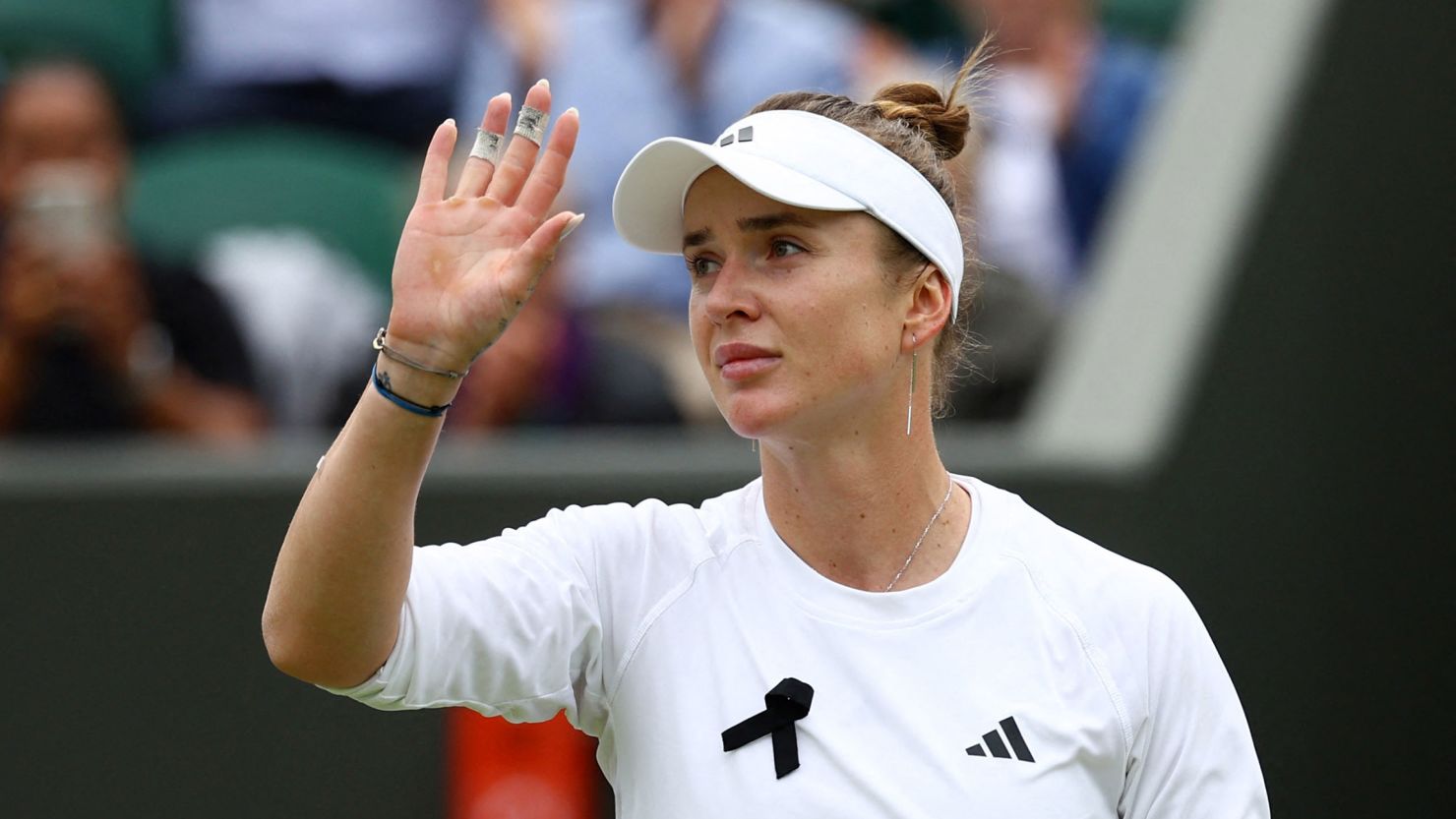 Ukraine's Elina Svitolina, wearing a black ribbon on her uniform, waves after winning her fourth-round match against China's Xinyu Wang on Monday.