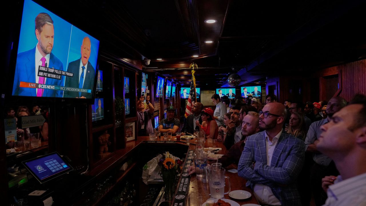 Sen. JD Vance and Minnesota Gov. Tim Walz are seen on a television at a watch party hosted by the New York Young Republican Club in New York on Tuesday.