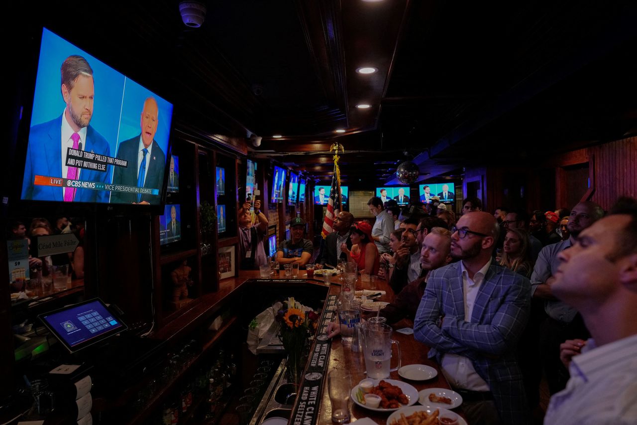 Sen. JD Vance and Minnesota Gov. Tim Walz are seen on a television at a watch party hosted by the New York Young Republican Club in New York on Tuesday.