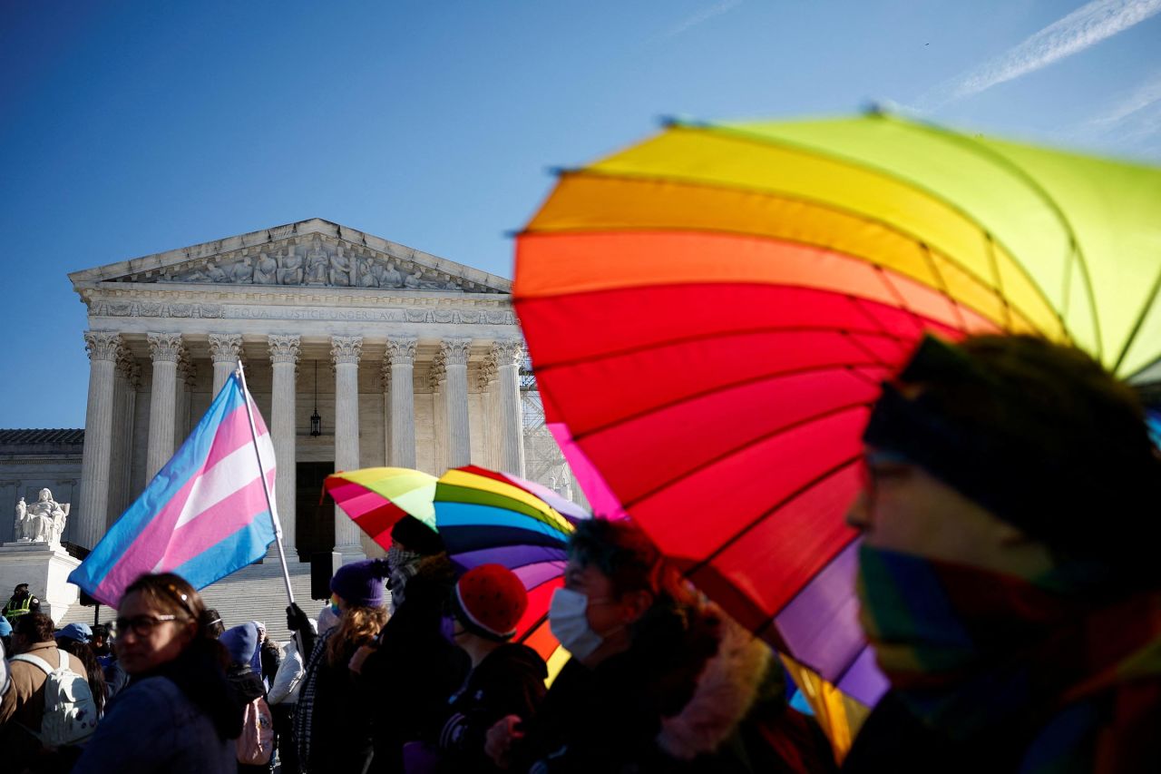 People hold rainbow-colored umbrellas and flags at a demonstration as the US Supreme Court hears arguments over an appeal by President Joe Biden's administration of a lower court's decision upholding a Republican-backed ban in Tennessee on gender-affirming medical care for transgender minors, outside the court in Washington, DC, on December 4. 