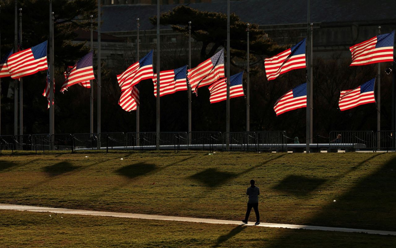 A person walks past flags flying at half-staff at the Washington Monument on the National Mall on Monday.