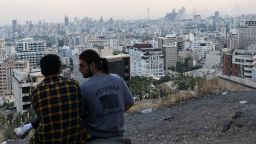 A man wears a US veteran-themed shirt, that reads, "United we stand", as smoke rises in the distance, following an Israeli attack on the IRIB building, the country's state broadcaster, in Tehran, Iran, on June 16.