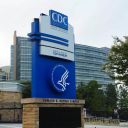 The logo of Center of Disease Control and Prevention (CDC) is seen as the glass of it's building in the background is pockmarked by bullet holes, following a deadly shooting incident in Atlanta, Georgia, on August 9, 2025.