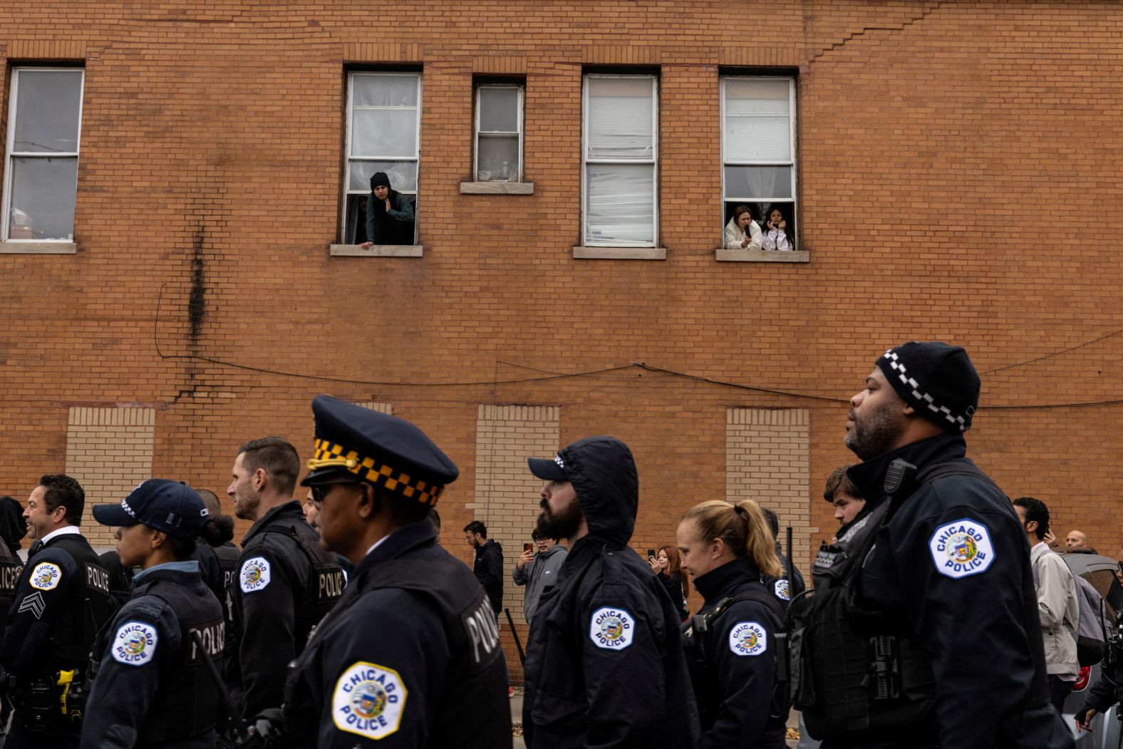 Local residents watch Chicago police officers leave the area after an immigration raid in the city’s Little Village neighborhood on Saturday, November 8.