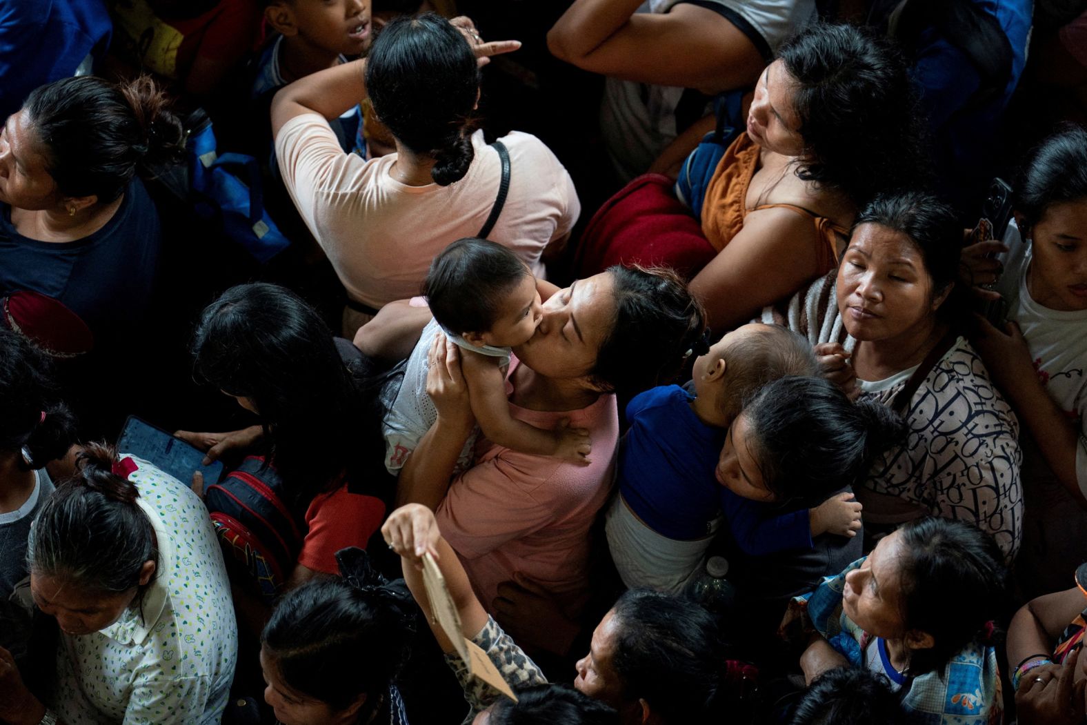 A woman kisses a child as they line up to register at an evacuation center in Manila, Philippines, on Sunday, November 9. <a href="index.php?page=&url=https%3A%2F%2Fwww.cnn.com%2F2025%2F11%2F08%2Fasia%2Fphilippines-typhoon-fung-wong-uwan-hnk-intl">Typhoon Fung-wong</a> triggered floods and landslides, cut power to entire provinces and killed at least four people before barreling out of the Philippines on Monday.