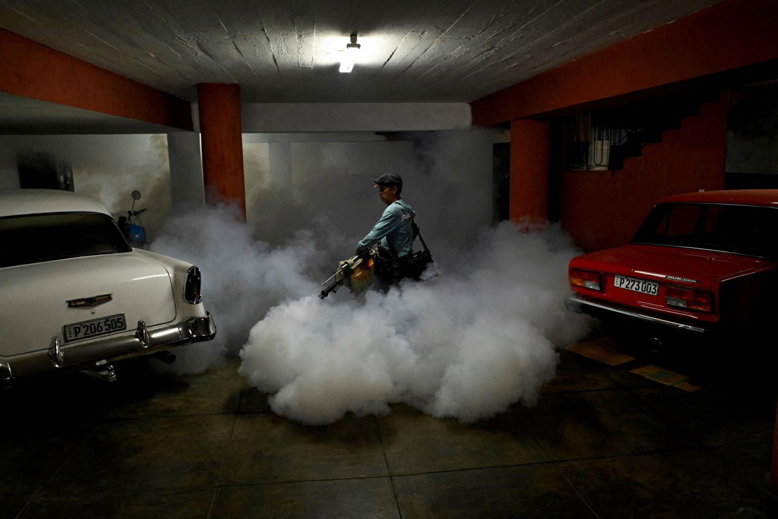 State worker Arnaldo Alvarez uses a fogging machine to fumigate a garage in Havana, Cuba, on Thursday, November 13. It was part of a public health campaign against the spread of the mosquito-transmitted chikungunya virus.