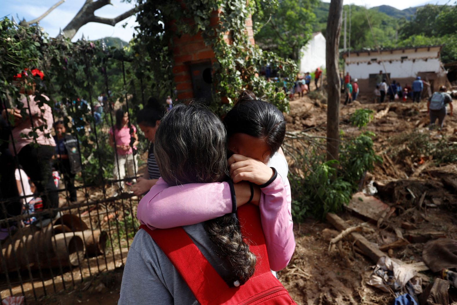 People react Tuesday, November 18, while standing in an area damaged by a deadly landslide in Achira, Bolivia. The landslide came after six hours of torrential rain.